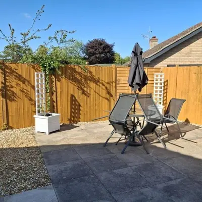 two chairs and an umbrella on a patio at Hazel Cottage in Mildenhall