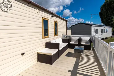 a deck with a couch and chairs on a building at Caravan Hire Mersea Island - EOEPS in East Mersea