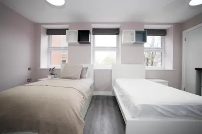 two beds in a room with two windows at Ryegate House Colchester in Colchester
