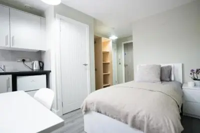 a white bedroom with a bed and a kitchen at Ryegate House Colchester in Colchester