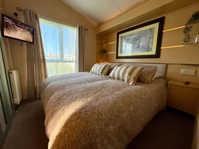 a bedroom with a large bed and a window at Stylish Inviting 2 Bedroom Caravan with Sea View in East Mersea
