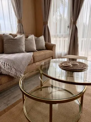 a living room with a couch and two glass tables at Stylish Inviting 2 Bedroom Caravan with Sea View in East Mersea
