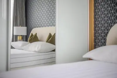 a mirror reflection of a bed in a bedroom at Luxurious City Centre Apartment in Chelmsford with Sky TV, Sports, Movies & Netflix in Chelmsford
