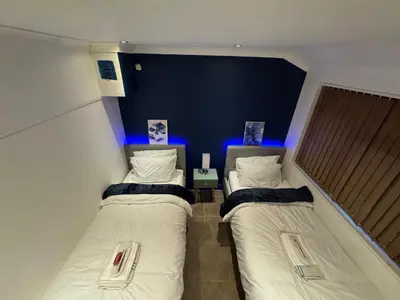 two beds in a small room with blue lights at Secret Escape in Cherry Hinton