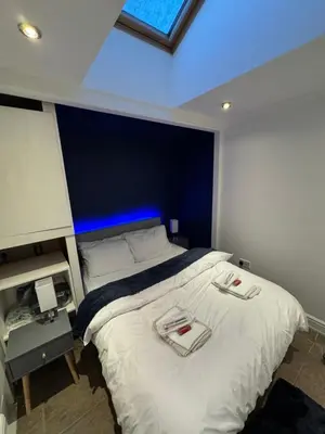 a bedroom with a large white bed with a blue ceiling at Secret Escape in Cherry Hinton