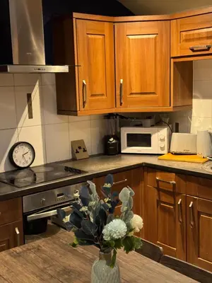 a kitchen with wooden cabinets and a vase with flowers at Secret Escape in Cherry Hinton