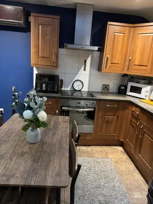 a kitchen with a wooden table with a vase of flowers on it at Secret Escape in Cherry Hinton