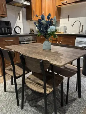 a kitchen table with a vase of flowers on it at Secret Escape in Cherry Hinton