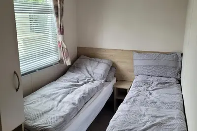 a small bedroom with two beds and a window at Highfield Grange Holiday Park in Clacton-on-Sea