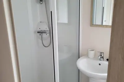 a white bathroom with a toilet and a sink at Highfield Grange Holiday Park in Clacton-on-Sea