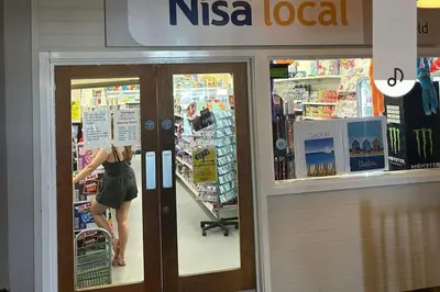 a woman is standing outside of a nsa local store at Highfield Grange Holiday Park in Clacton-on-Sea