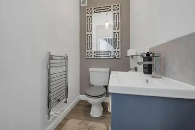 a bathroom with a toilet and a sink and a mirror at Spacious 5 Bedroom Detached Property with parking in Bury Saint Edmunds