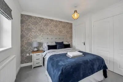 a bedroom with a bed with a blue comforter at Spacious 5 Bedroom Detached Property with parking in Bury Saint Edmunds