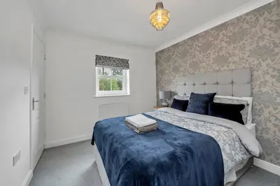 a bedroom with a large bed with a blue blanket at Spacious 5 Bedroom Detached Property with parking in Bury Saint Edmunds