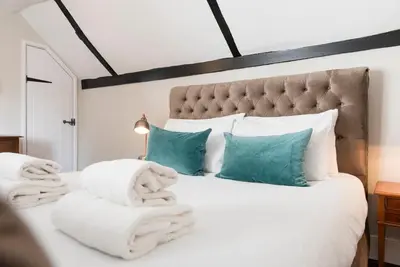a bedroom with a white bed with towels on it at The Book Nook, Woodbridge in Woodbridge