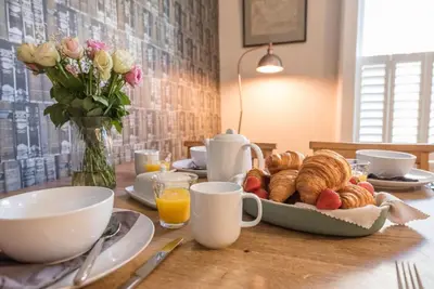 a table with a plate of pastries and a vase of flowers at The Book Nook, Woodbridge in Woodbridge