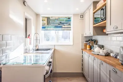 a kitchen with white cabinets and a window at The Book Nook, Woodbridge in Woodbridge