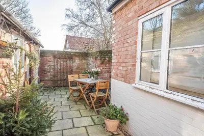 a patio with a table and chairs on a brick wall at The Book Nook, Woodbridge in Woodbridge