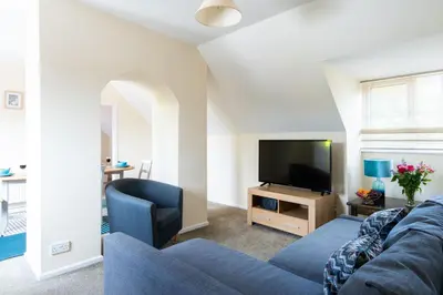 a living room with a blue couch and a tv at Dolphin Apartment, Thorpeness - Only a short stroll from the Beach, Thorpeness Lake, Country Club and Golf Club in Thorpeness