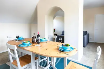 a dining room with a wooden table and chairs at Dolphin Apartment, Thorpeness - Only a short stroll from the Beach, Thorpeness Lake, Country Club and Golf Club in Thorpeness