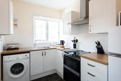 a kitchen with white cabinets and a dishwasher at Dolphin Apartment, Thorpeness - Only a short stroll from the Beach, Thorpeness Lake, Country Club and Golf Club in Thorpeness