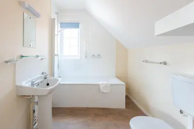 a white bathroom with a sink and a bath tub at Dolphin Apartment, Thorpeness - Only a short stroll from the Beach, Thorpeness Lake, Country Club and Golf Club in Thorpeness