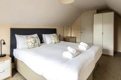 a bedroom with a large white bed with towels on it at Dolphin Apartment, Thorpeness - Only a short stroll from the Beach, Thorpeness Lake, Country Club and Golf Club in Thorpeness