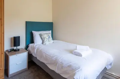 a bedroom with a bed with a blue headboard and a night stand at Dolphin Apartment, Thorpeness - Only a short stroll from the Beach, Thorpeness Lake, Country Club and Golf Club in Thorpeness