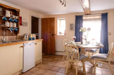 a kitchen and dining room with a table and chairs at Barleys Cottage - Aldeburgh Coastal Cottages in Aldeburgh