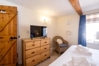 a bedroom with a tv and a dresser with a bed at Barleys Cottage - Aldeburgh Coastal Cottages in Aldeburgh