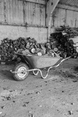 a wheelbarrow filled with a pile of logs at 'Bramley' Hut on private farm in Charsfield