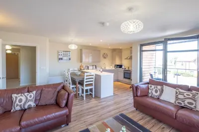 a living room with a couch and a kitchen at 3 King Georges House - Aldeburgh Coastal Cottages in Aldeburgh