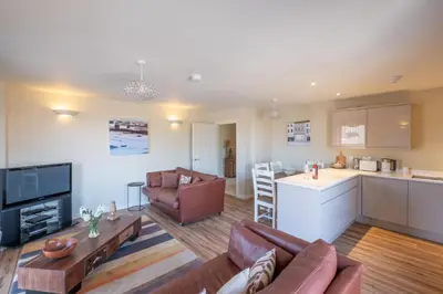 a living room with a couch and a kitchen at 3 King Georges House - Aldeburgh Coastal Cottages in Aldeburgh