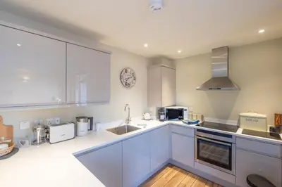 a kitchen with white cabinets and a sink at 3 King Georges House - Aldeburgh Coastal Cottages in Aldeburgh