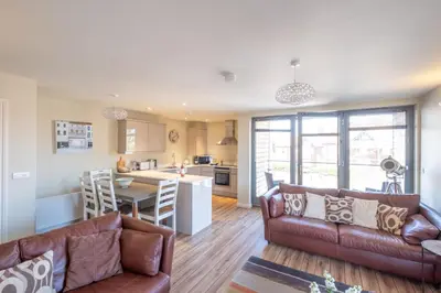 a living room with a couch and a table and a kitchen at 3 King Georges House - Aldeburgh Coastal Cottages in Aldeburgh