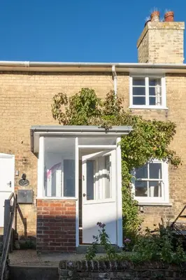 a white front door of a brick house at Ginnys Cottage by Aldeburgh Coastal Cottages in Aldeburgh