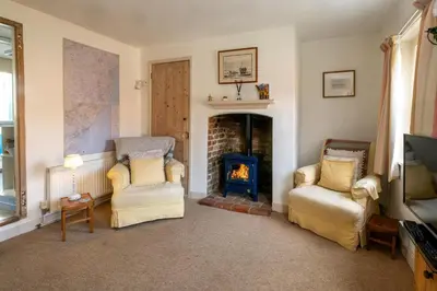 a living room with two chairs and a fireplace at Ginnys Cottage by Aldeburgh Coastal Cottages in Aldeburgh