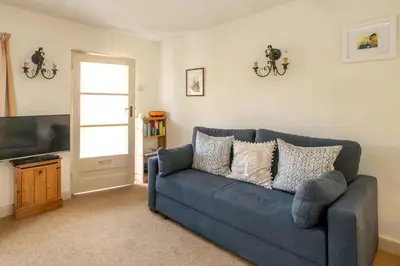 a blue couch in a living room with a tv at Ginnys Cottage by Aldeburgh Coastal Cottages in Aldeburgh