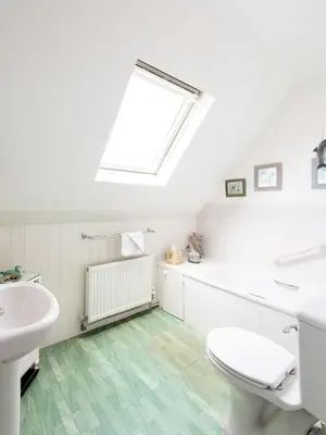 a bathroom with a toilet and a sink and a window at 2 Admirals Walk by Aldeburgh Coastal Cottages in Thorpeness