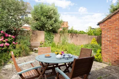 a patio table with chairs and a tea set on it at 2 Admirals Walk by Aldeburgh Coastal Cottages in Thorpeness