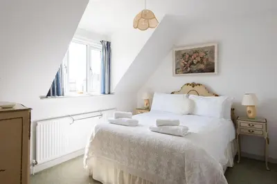 a bedroom with a white bed with towels on it at 2 Admirals Walk by Aldeburgh Coastal Cottages in Thorpeness