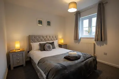 a bedroom with a bed with two lamps and a window at Hampstead Avenue in Great Clacton