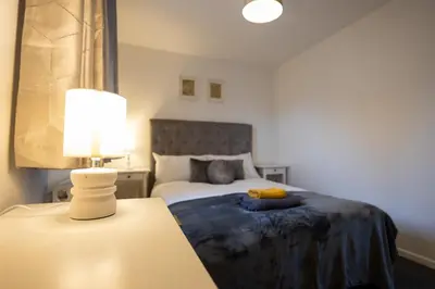 a bedroom with a bed and a lamp on a table at Hampstead Avenue in Great Clacton
