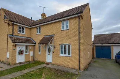 a yellow brick house with white doors and a garage at Hampstead Avenue in Great Clacton