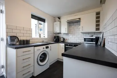 a white kitchen with a washing machine in it at Hampstead Avenue in Great Clacton
