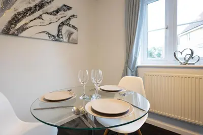 a dining room with a glass table and two wine glasses at Hampstead Avenue in Great Clacton