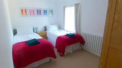 two beds in a small room with red blankets at Fully Refurbished 3 bed Victorian Cottage in Tolleshunt D'Arcy in Tolleshunt DʼArcy
