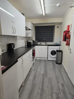 a kitchen with white cabinets and a washer and dryer at Barnfield Rooms in Chelmsford