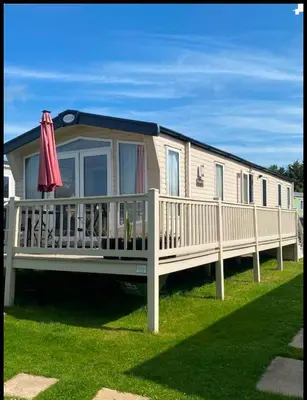 a mobile home with a deck and an umbrella at Weeley Bridge 3 Bedroom Luxury Holiday Home in Weeley