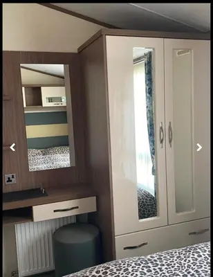 a bedroom with a cabinet and a mirror at Weeley Bridge 3 Bedroom Luxury Holiday Home in Weeley